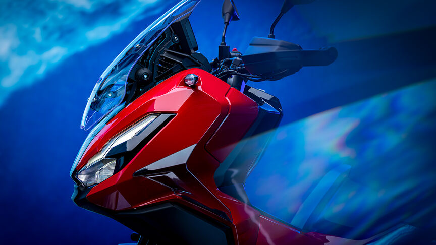 Trojštvrťový záber spredu na skúter Honda ADV350 na pobreží.