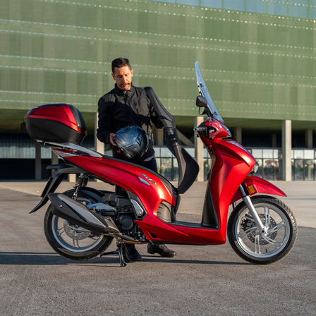 Honda SH350i, muž stojaci vedľa skútra, pohľad zozadu, červený motocykel