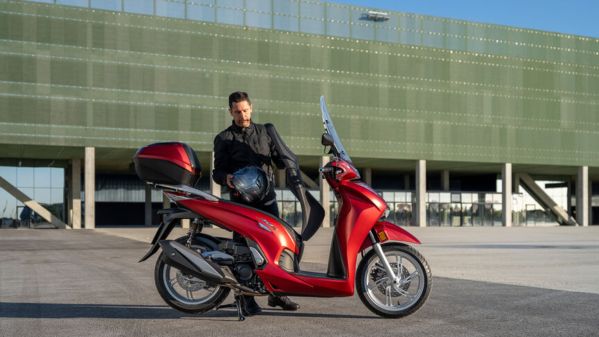 Honda SH350i, trojštvrťový predný záber z pravej strany, s jazdcom, na ceste, červený motocykel