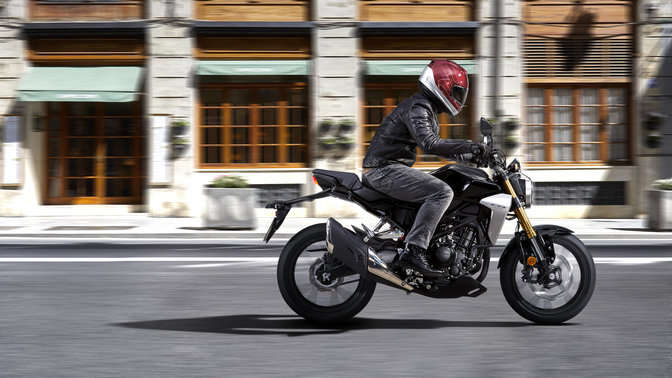 Bočný akčný záber motocykla Honda CB300R Neo Sports Café pri jazde po ceste.