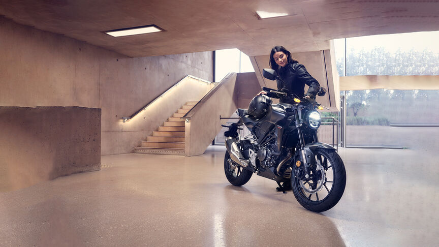 Trojštvrťový záber spredu na model Honda CB300R, na ktorý sa pozerajú ženy v štúdiu.