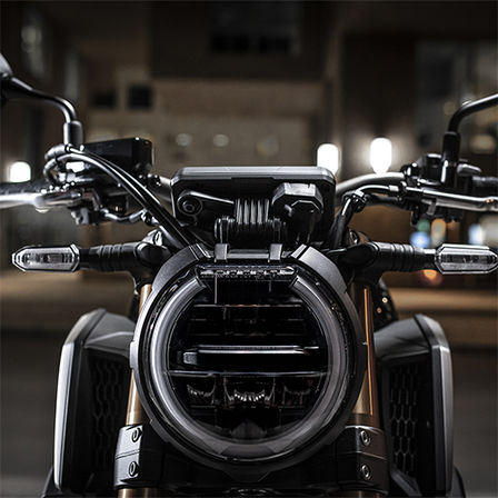 CB650R Neo Sports Café, priblížený pohľad spredu na predný svetlomet v nočnom meste 