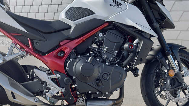 Honda CB750 Hornet s mužom opierajúcim sa o budovu.