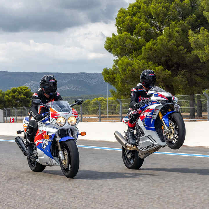 Pohľad zboku na tri modely Honda CBR1000RR-R Fireblade a Fireblade SP zaparkované na pretekárskej trati