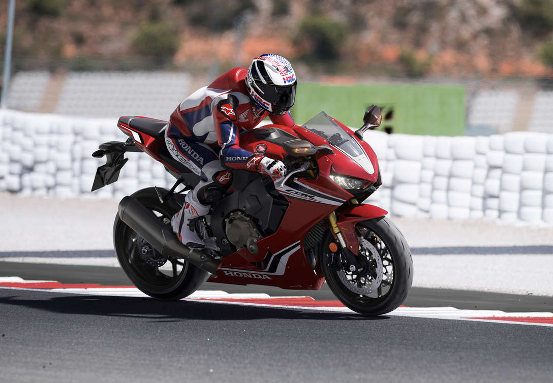 Pohľad na tri štvrtiny prednej časti modelu Honda CBR100RR Fireblade s jazdcom na pretekárskej trati.