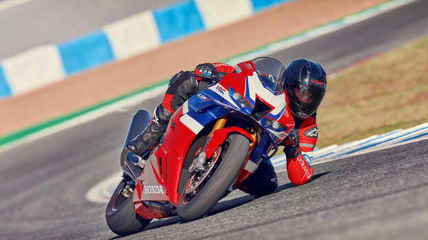 Dynamický záber na model Honda CBR1000rr-r Fireblade na trati s jazdcom zrýchľujúcim pri výjazde zo zákruty.