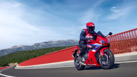 Pohľad zboku na motocykel Honda CBR650R zaparkovaný pred budovou. 